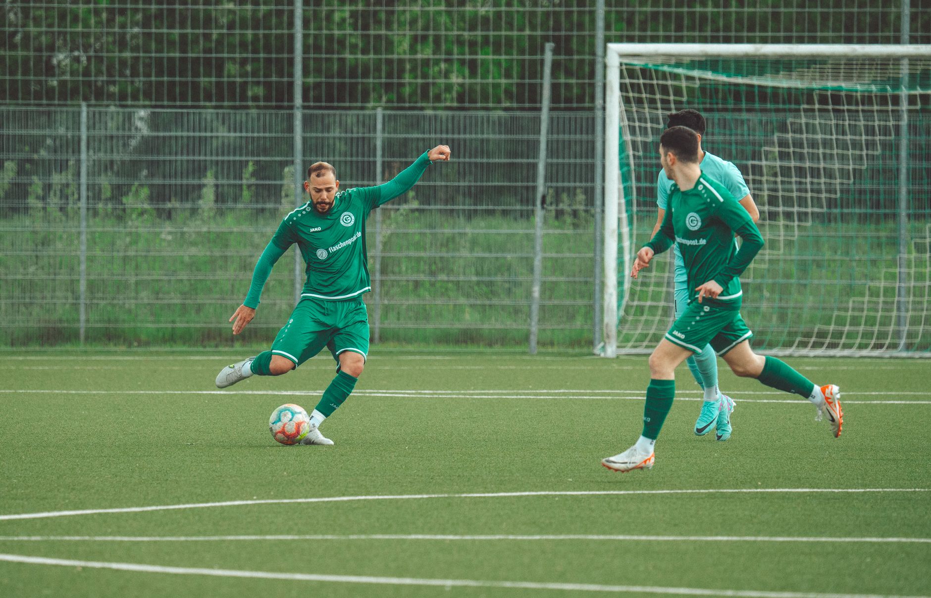 Players in green uniforms engage in a dynamic soccer match on a grassy field.