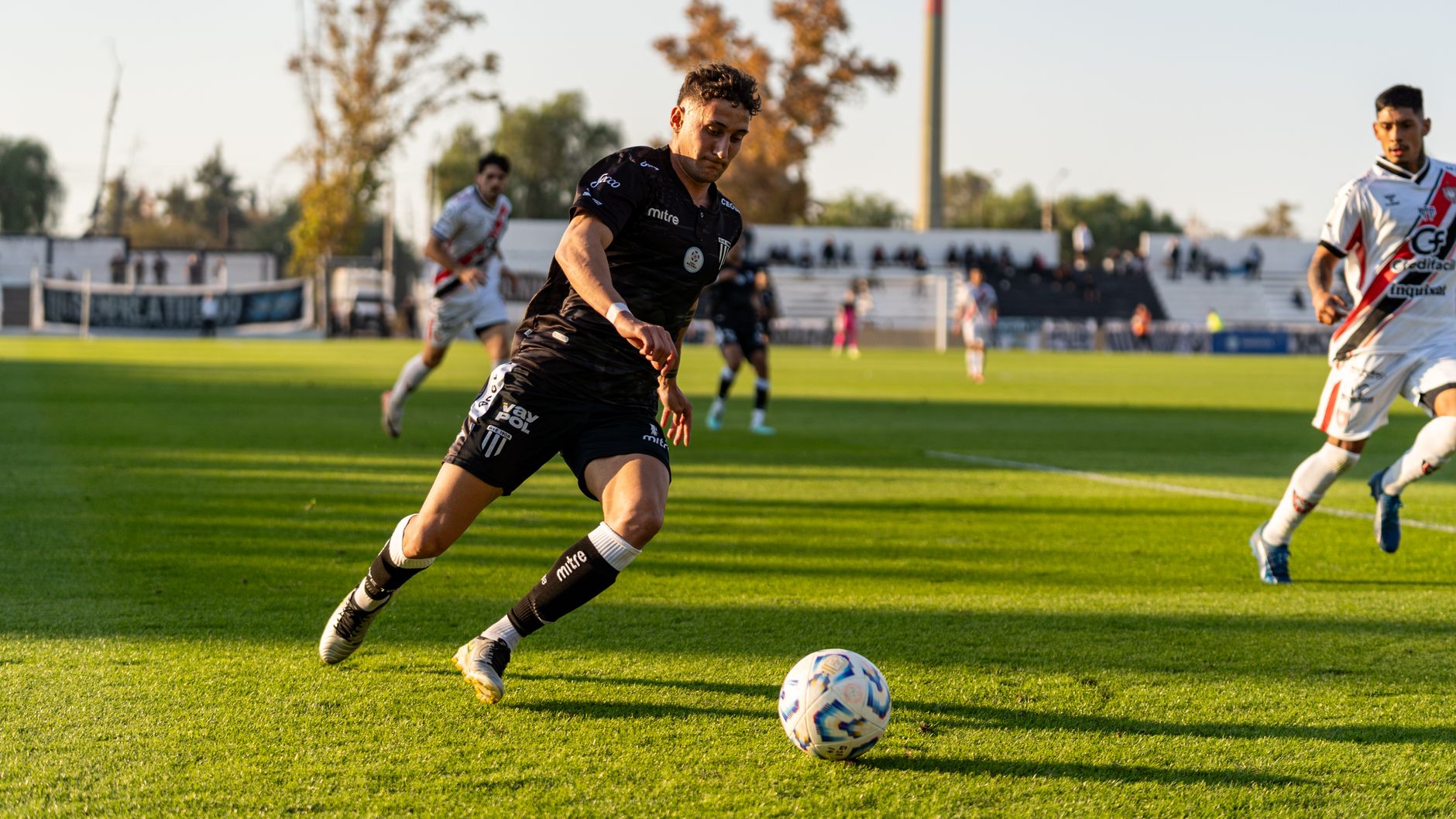 Dynamic action shot of a football match, capturing players in motion during a sunset game.