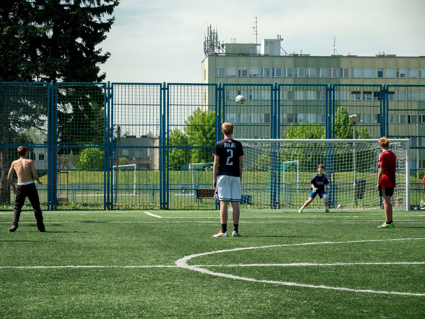 Teenagers enjoying a soccer game on an outdoor field in Wrocław, Poland.