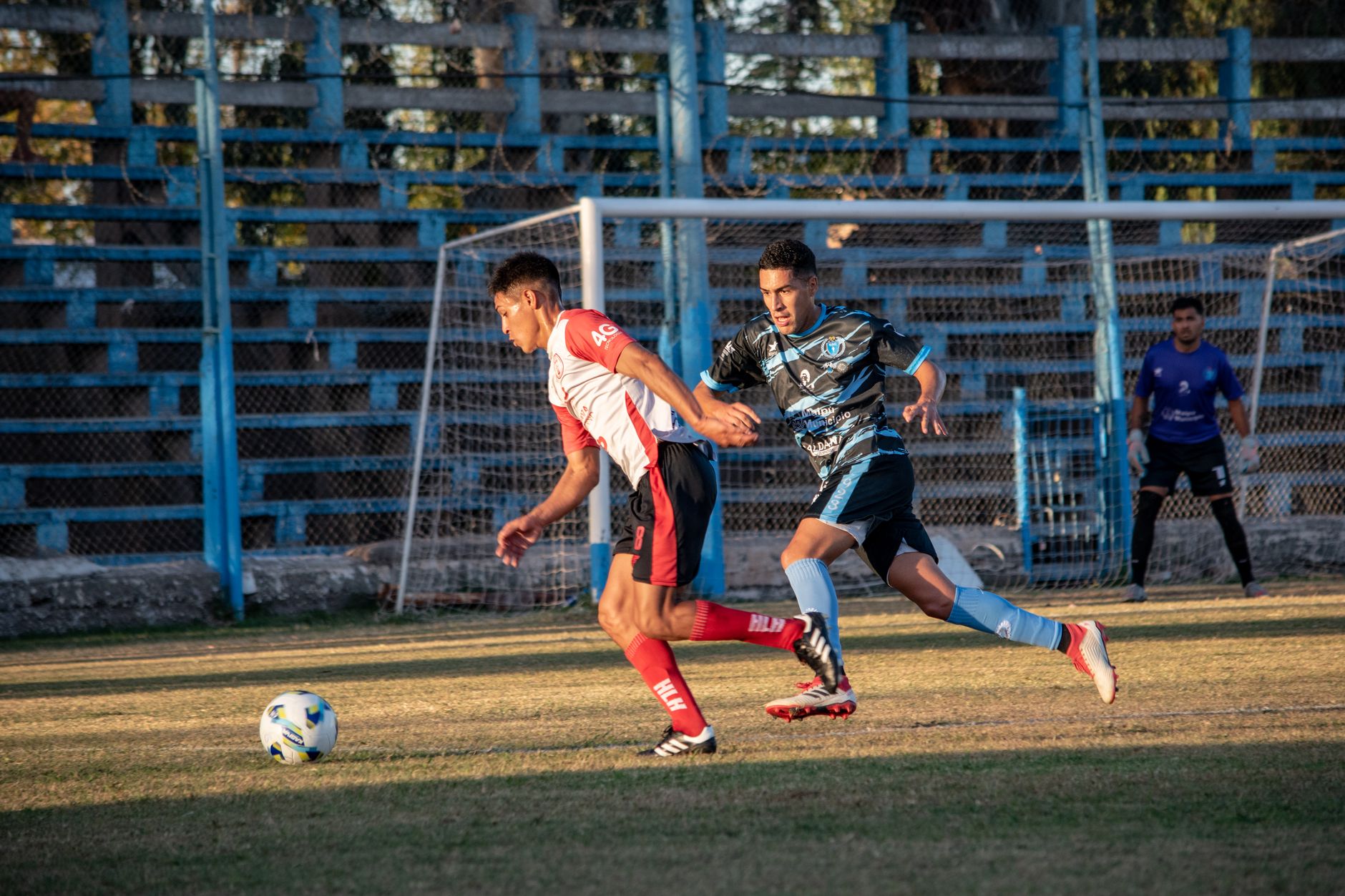 Footballers in action during a lively soccer match on a sunny day. Perfect for sports imagery.