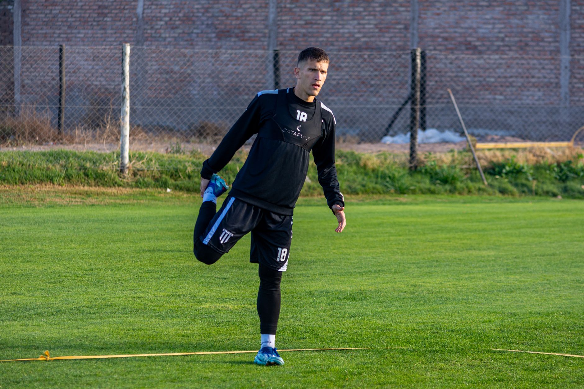 A football player stretching outdoors on the field during training for improved performance.