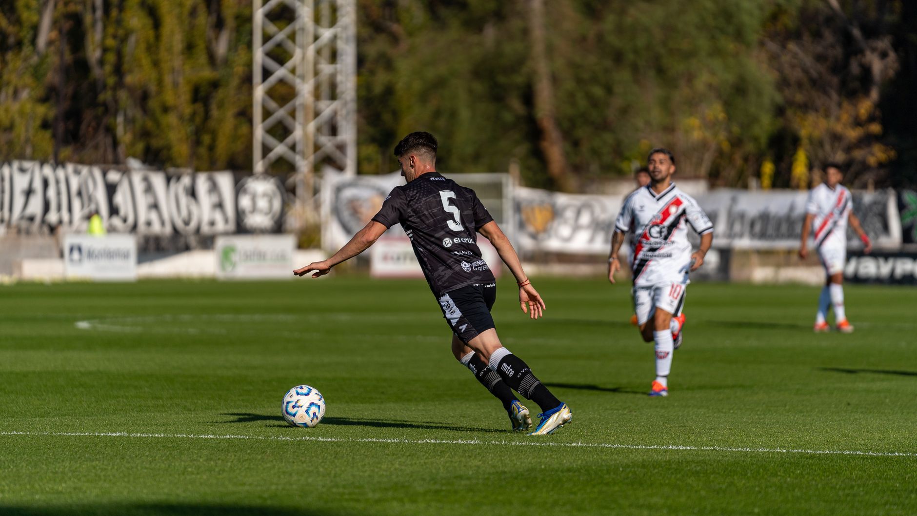 Dynamic outdoor soccer scene with players on a bright, sunlit day.
