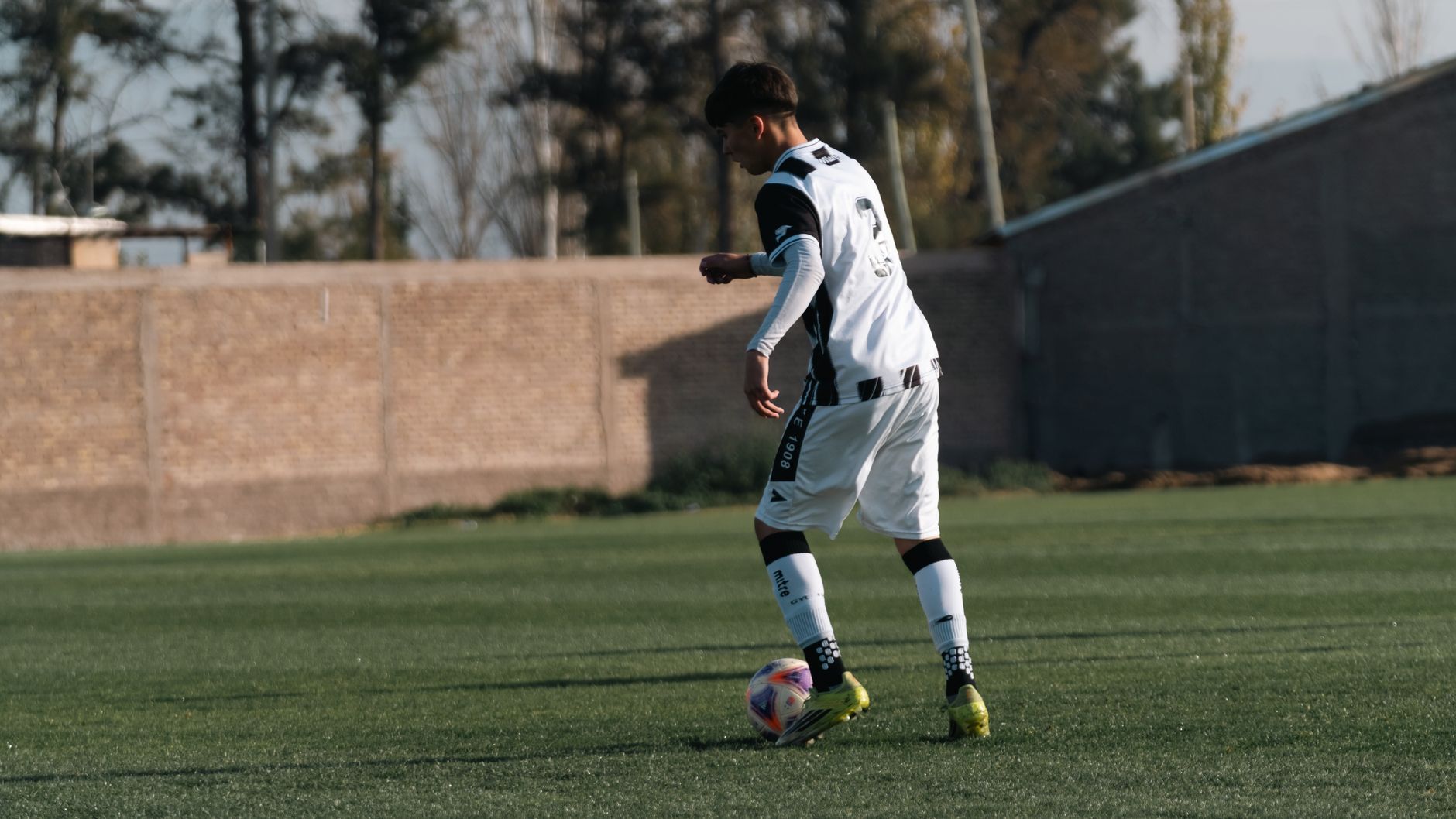 A young male soccer player in action on a green outdoor field during the day.