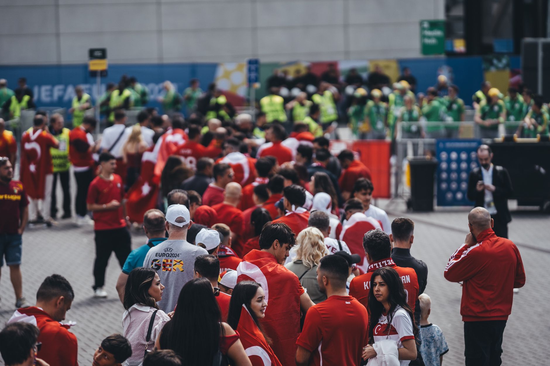A large group of fans in red jerseys queuing outdoors for a sports event entrance.