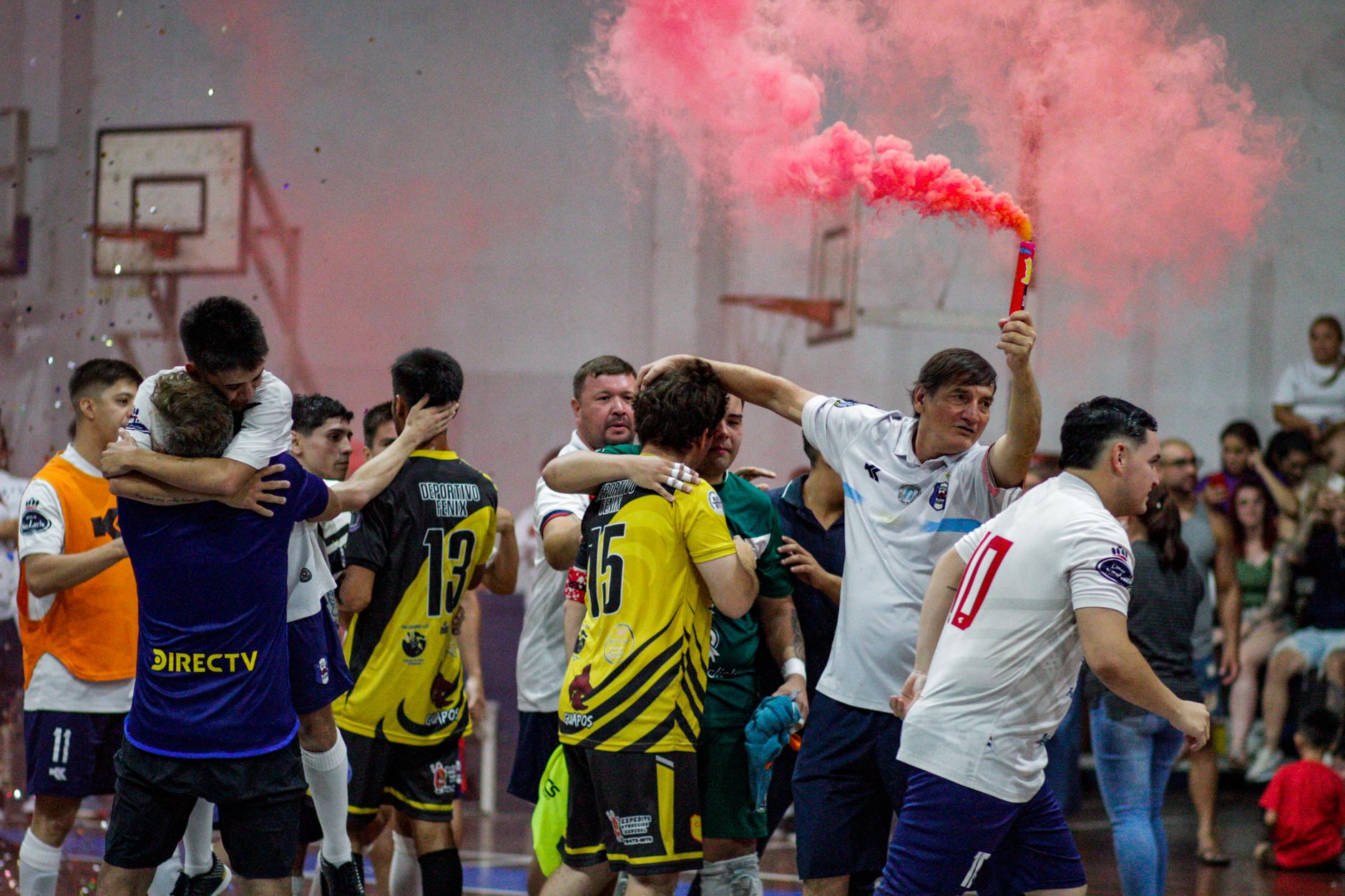 Joyful indoor soccer victory celebration with a vibrant pink smoke flare creating an energetic atmosphere.