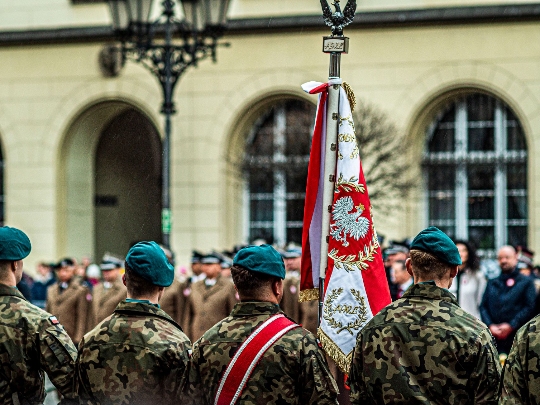 Polish soldiers in uniform during a ceremonial parade with national flag.