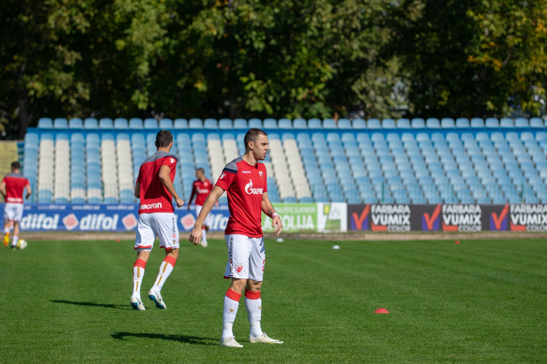Athletes practicing soccer on an outdoor field in team uniforms.