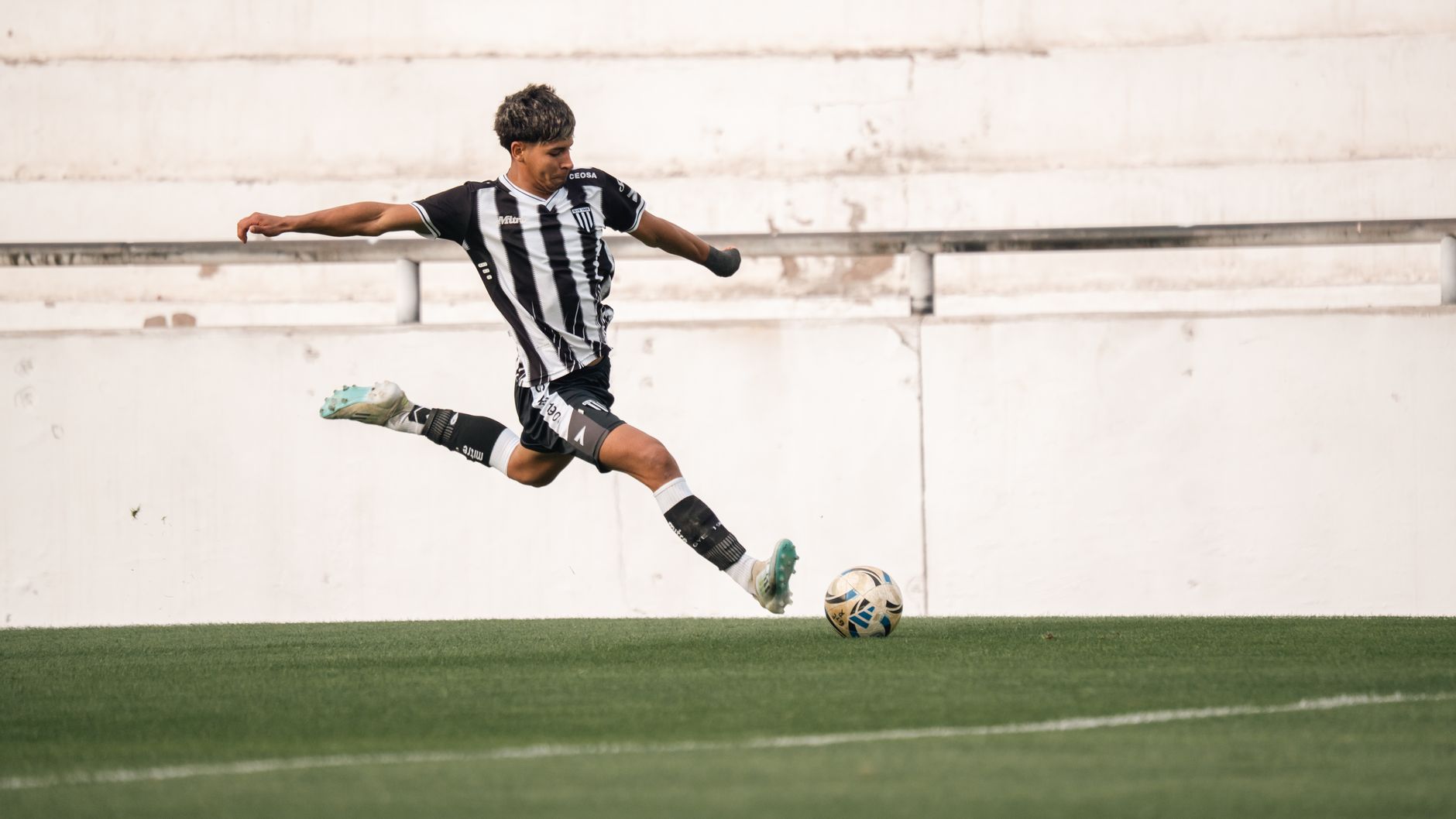 Dynamic shot of a soccer player in mid-air kick on green field.