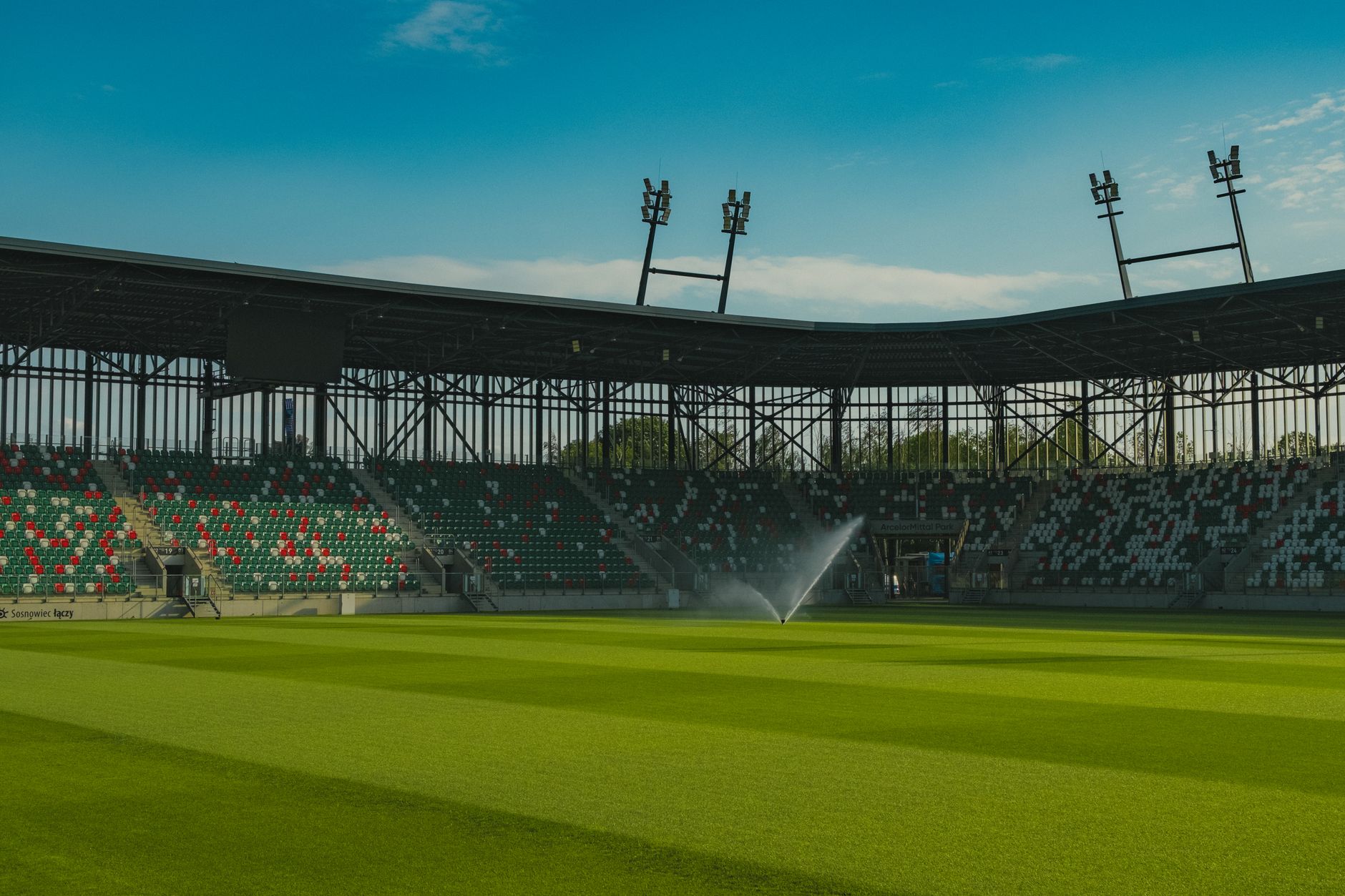Panoramic view of an empty football stadium in Sosnowiec, Poland, under a clear blue sky.