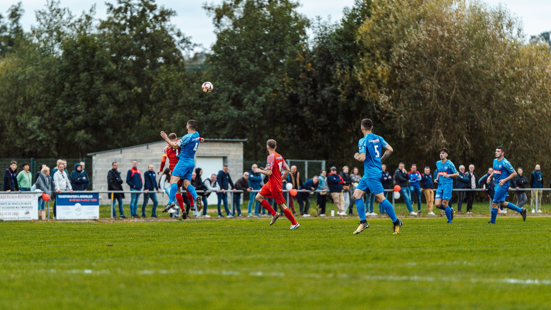 Players in blue and red compete intensely on a football field in France, capturing the spirit of the game.