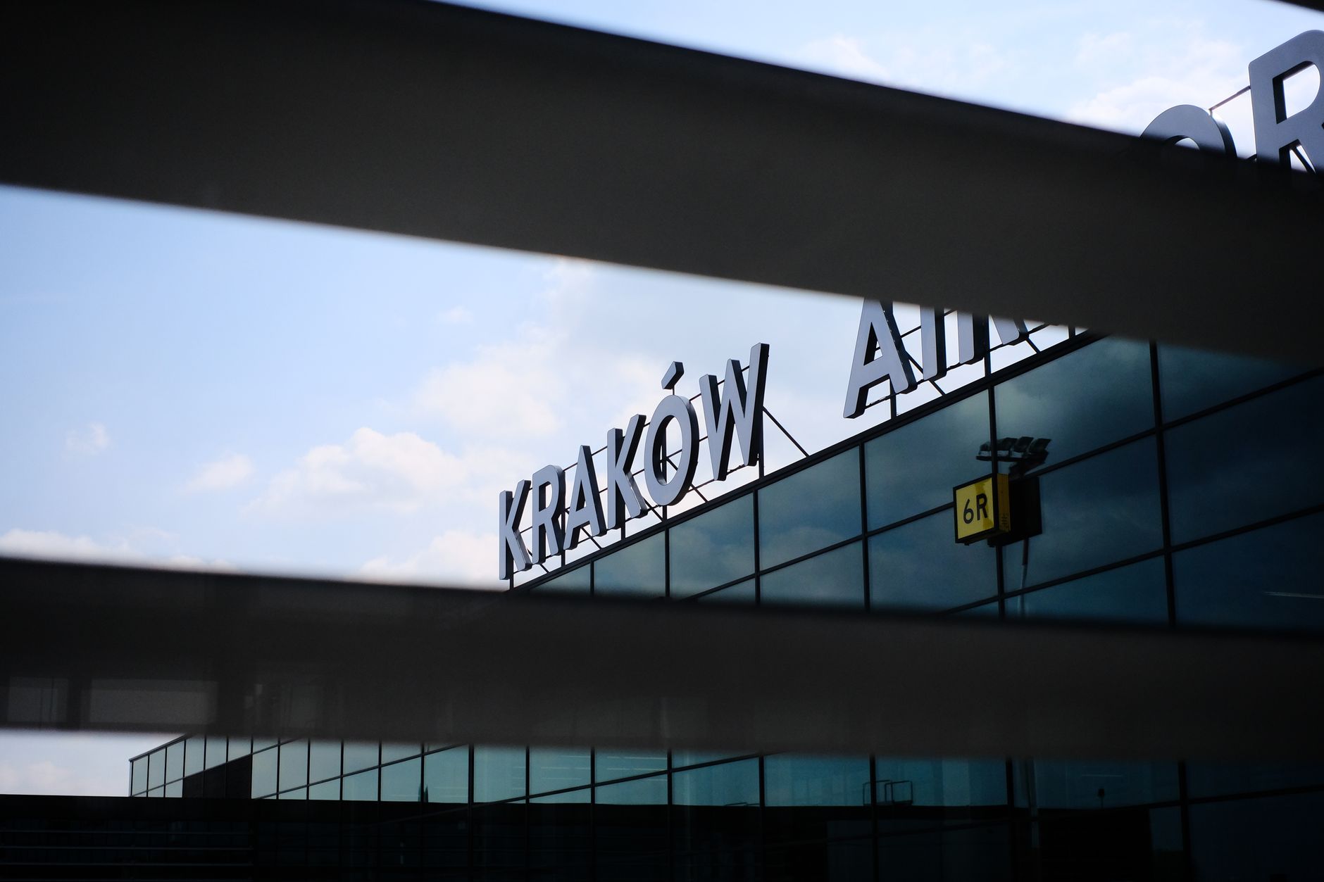 A modern architectural detail of the facade of Kraków Airport with reflective glass panels.