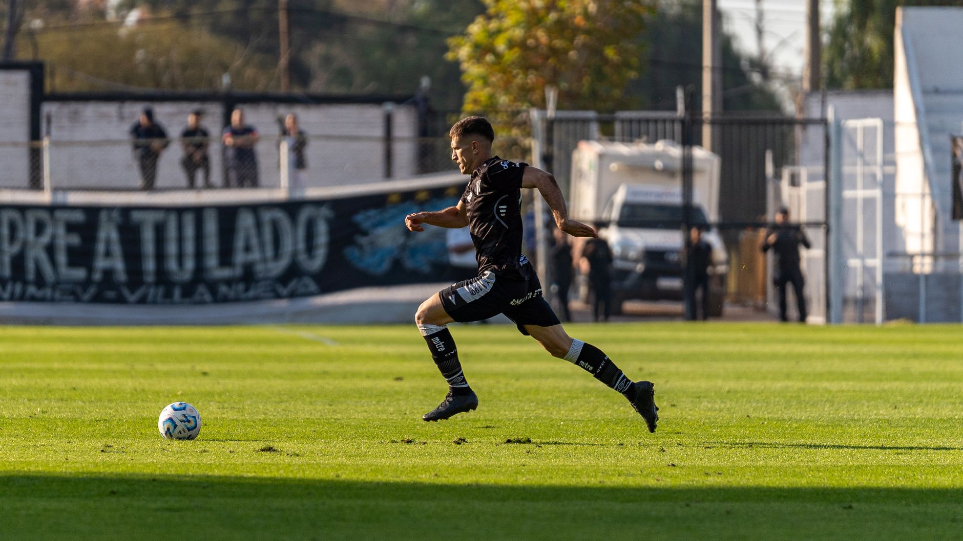 Football player running mid-game on a sunny day on the field, action and speed captured vividly.