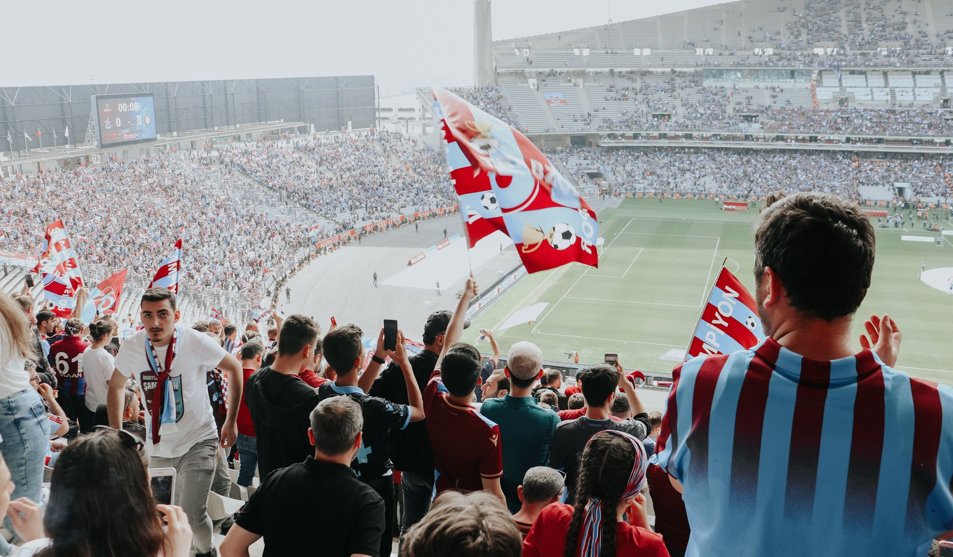 Soccer fans waving flags and celebrating victory in a packed stadium.