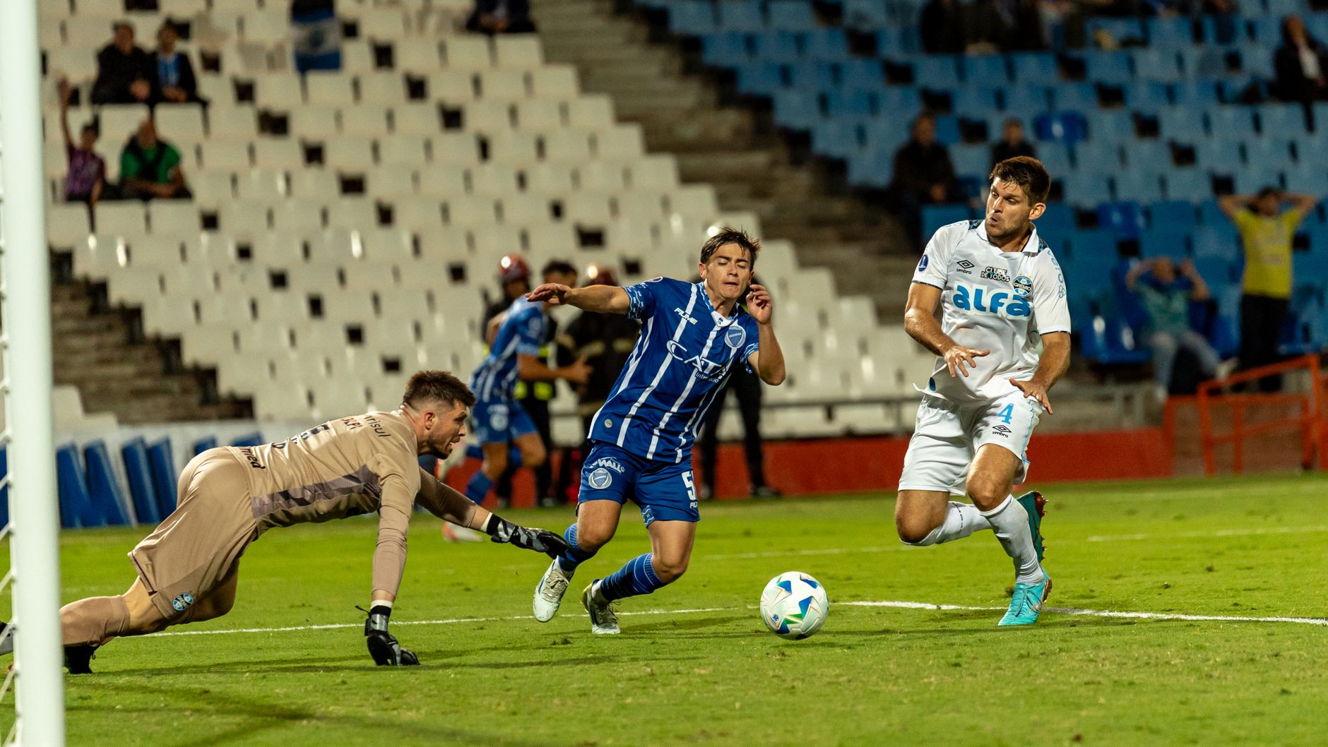 Soccer players in action near the goal during an intense match in a packed stadium.