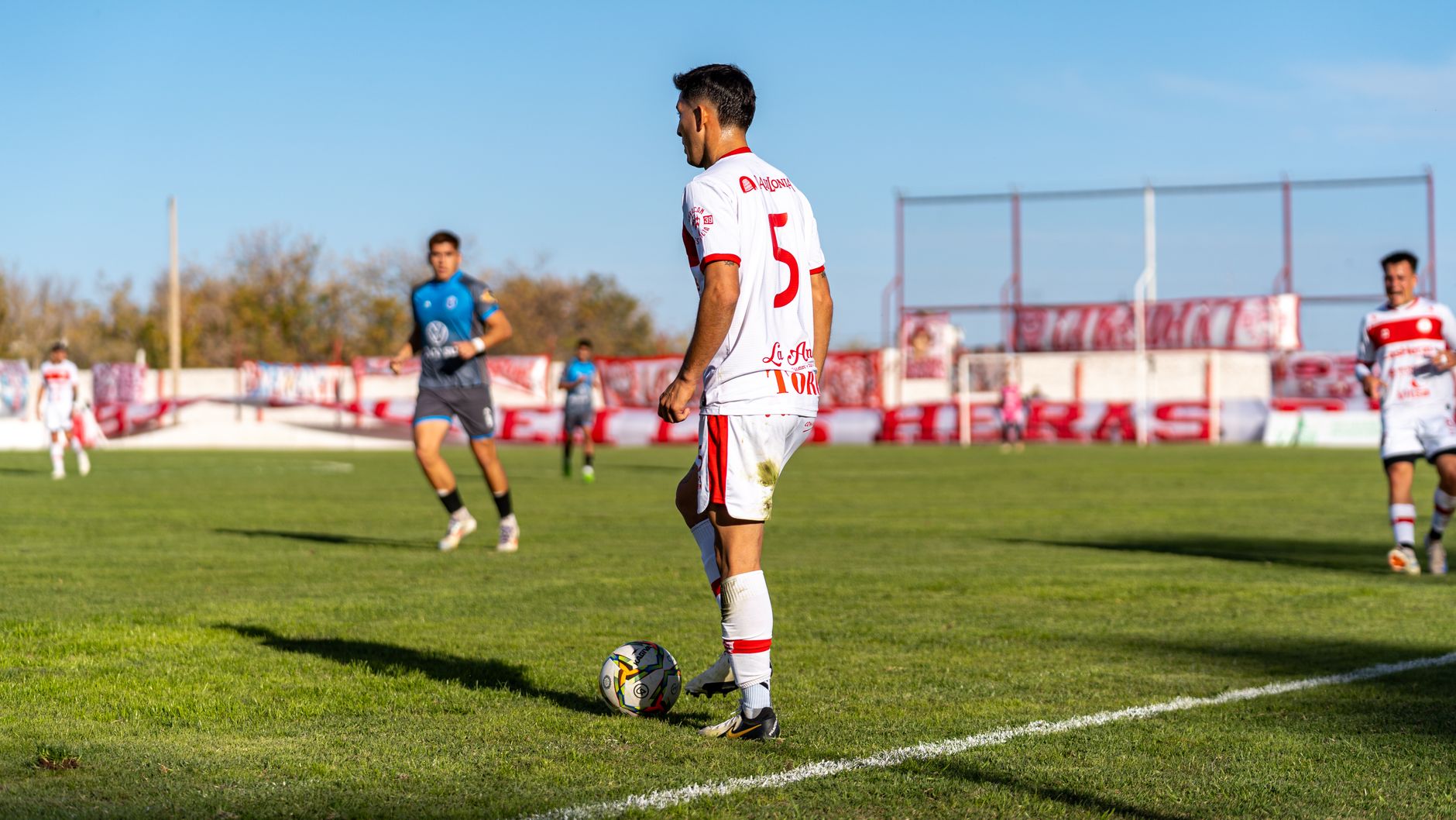 Soccer player in action during a daytime match on a sunny outdoor field.