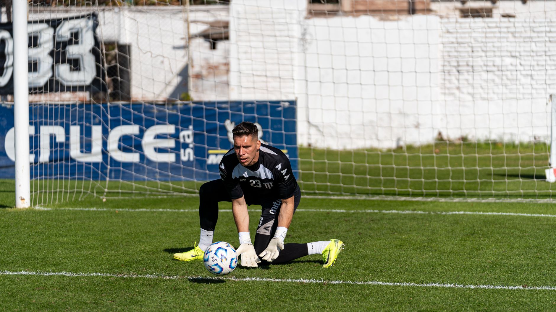 A goalkeeper in action making a save on a sunny day during a soccer match.