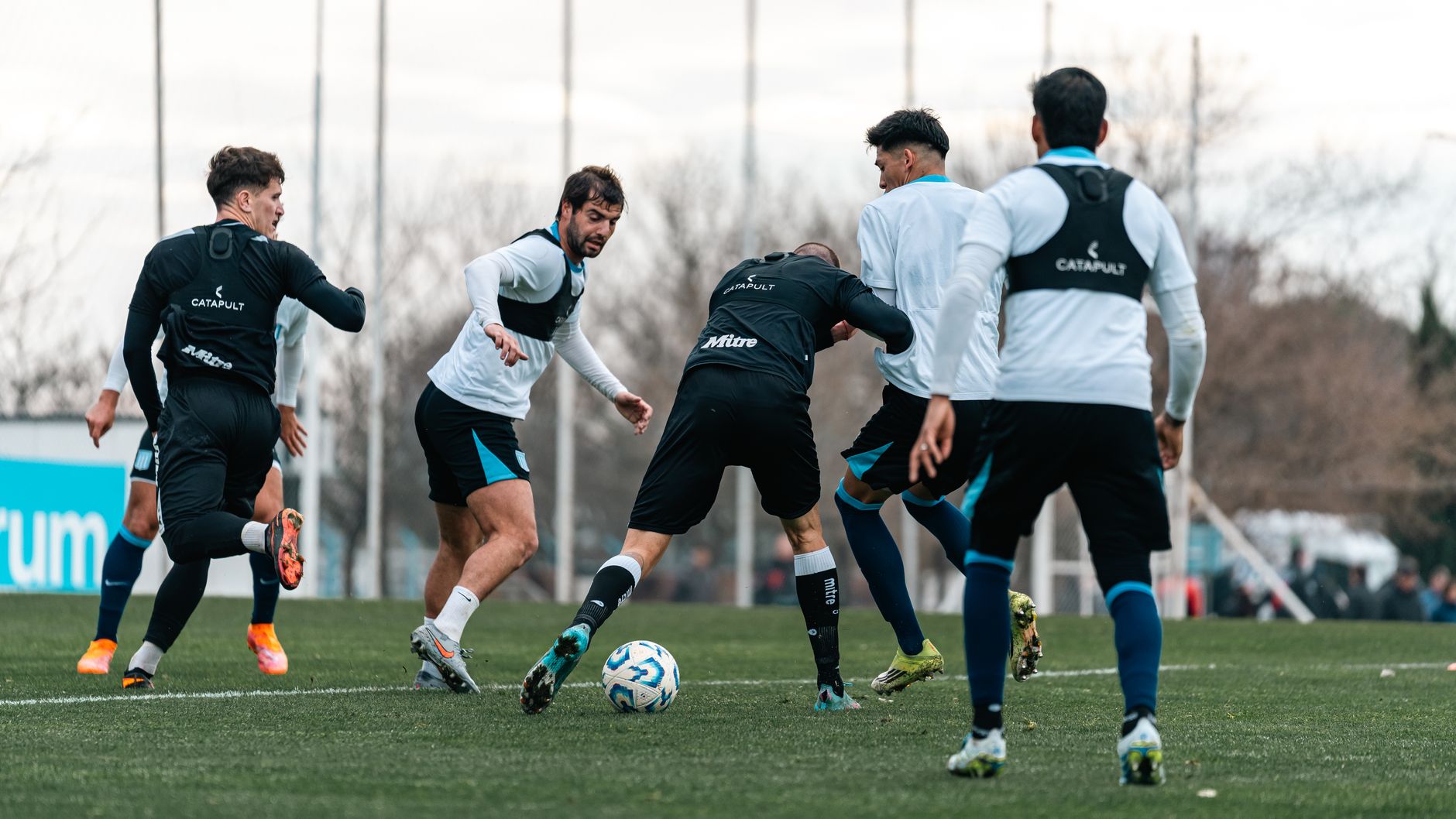 Group of male soccer players intensely training on a field during daytime.