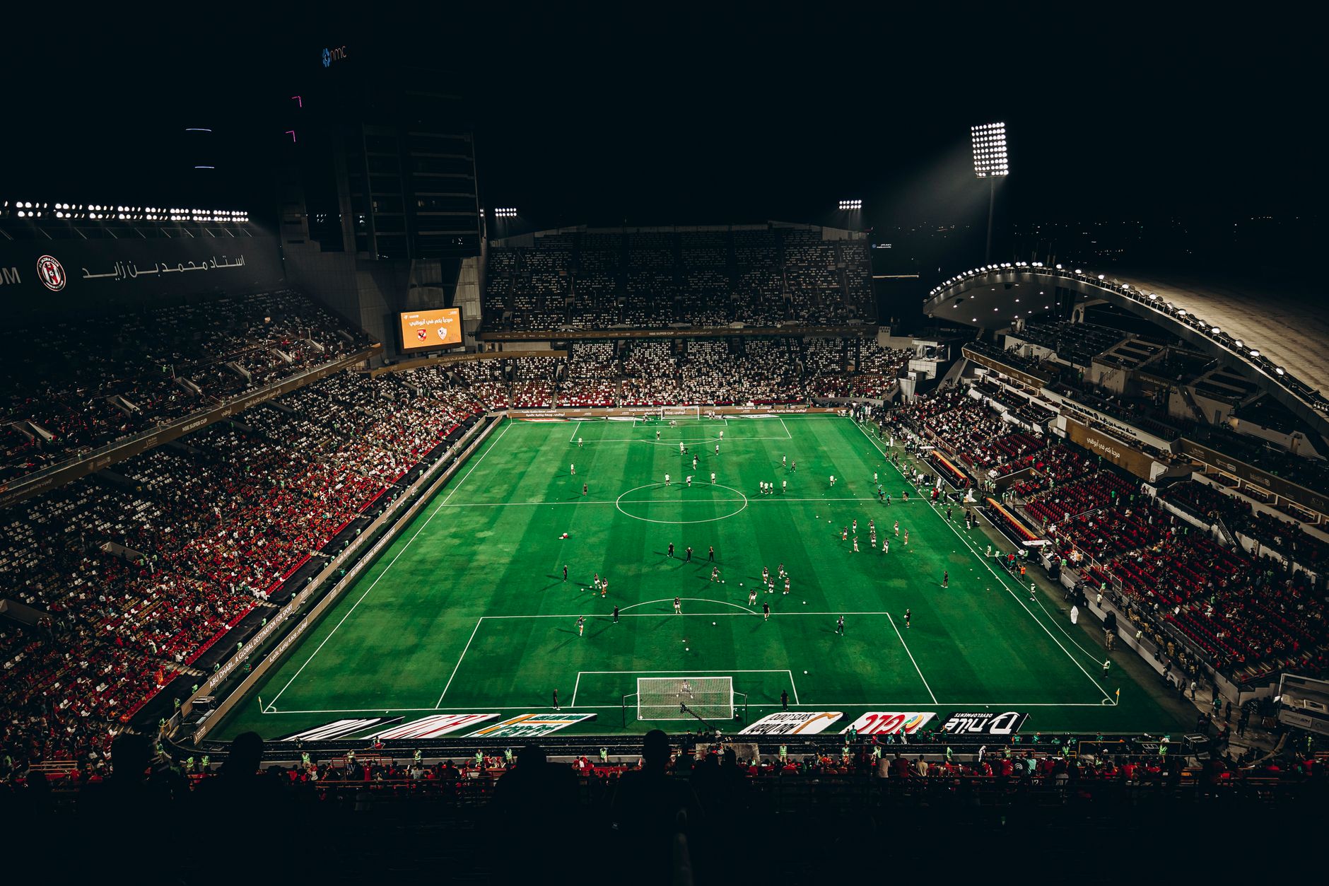 High-angle view of a vibrant football match with enthusiastic fans in a large stadium at night.
