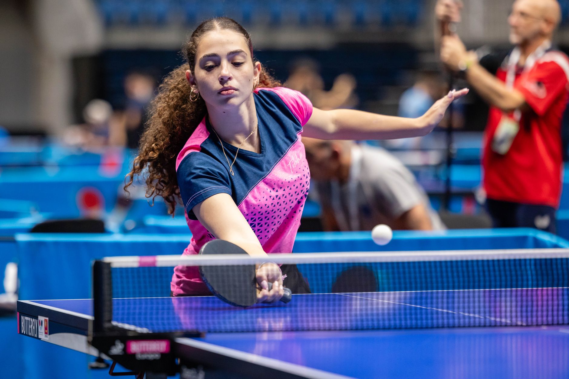 A female athlete intensely focused during a competitive table tennis match, showcasing skill and determination.