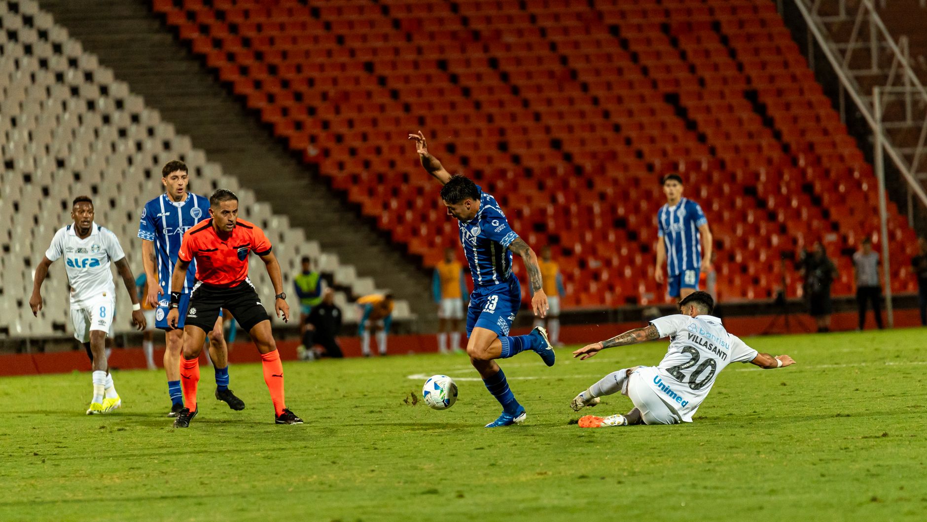Dynamic football match with players in action on a green field under stadium lights.