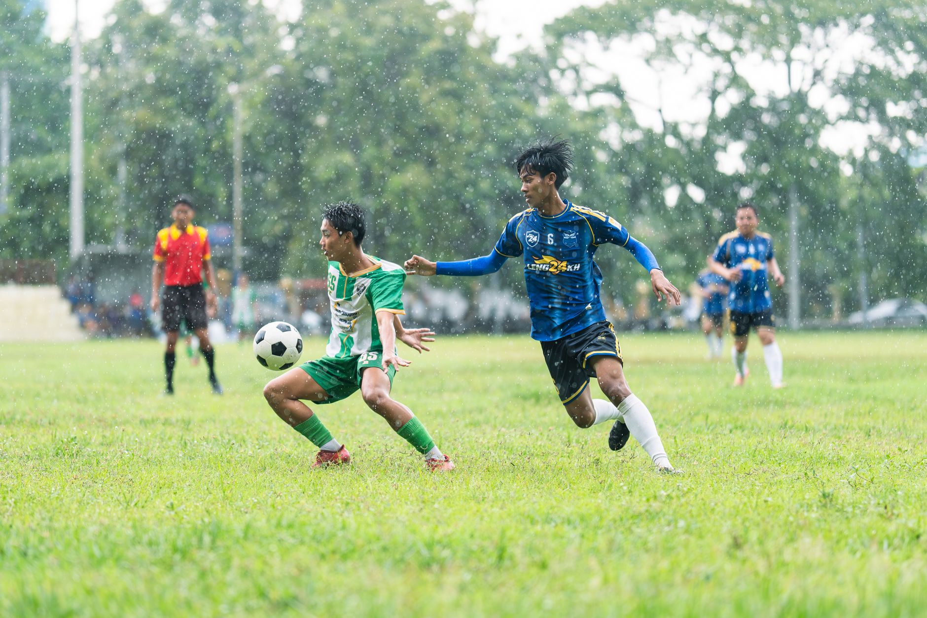 Soccer players compete fiercely during a rainy outdoor match.