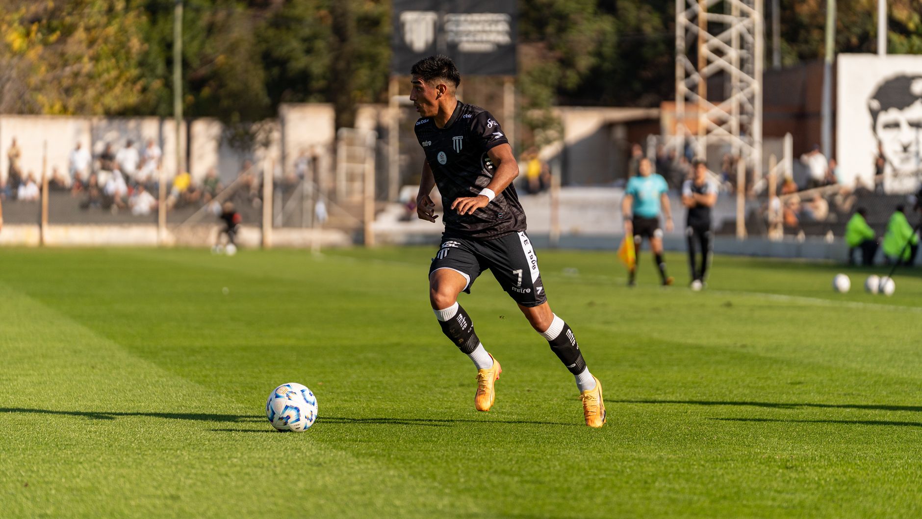 Soccer player dribbling the ball during a daytime match outdoors.