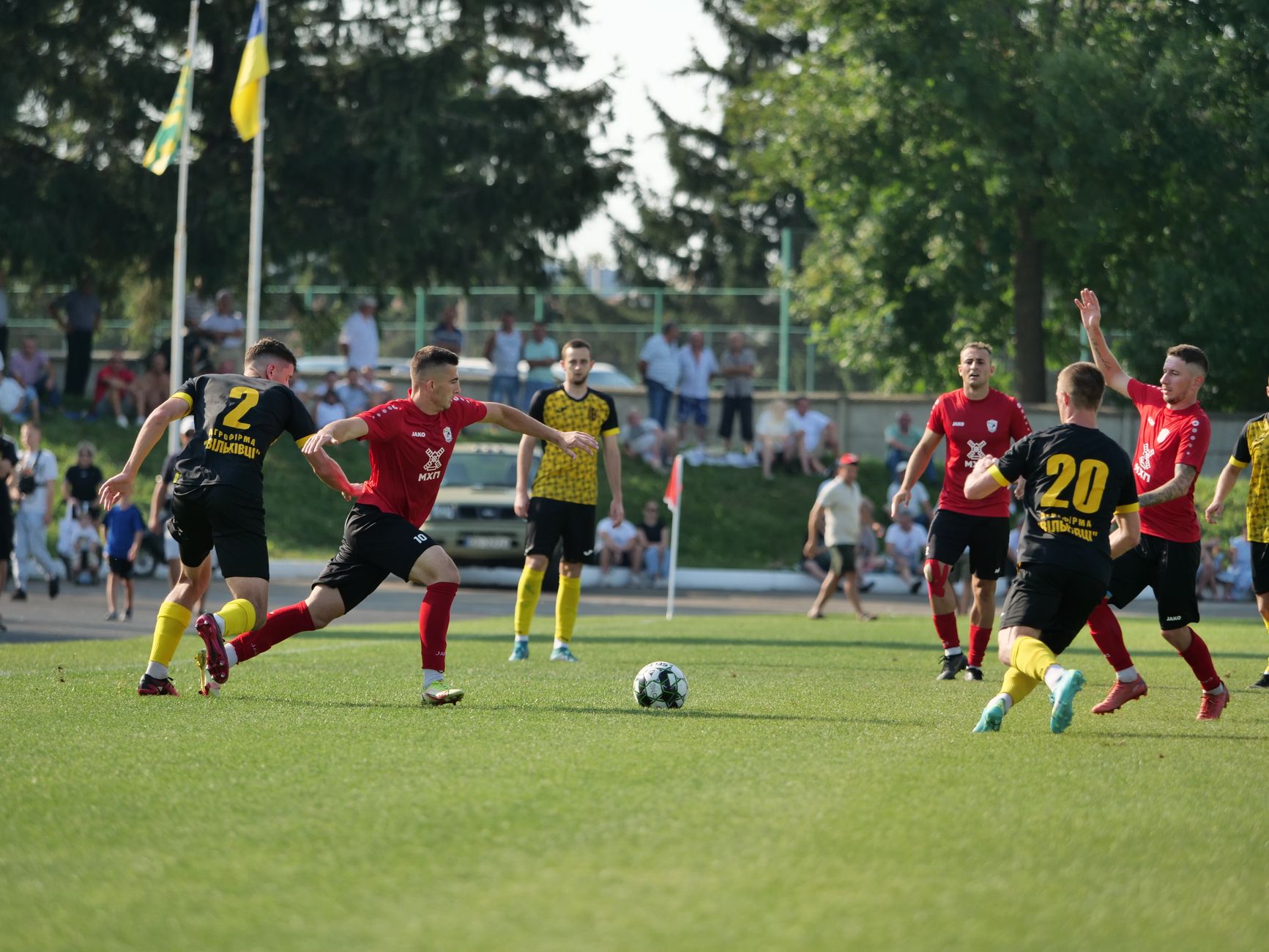 Dynamic action during a football match with teams in black and red jerseys.