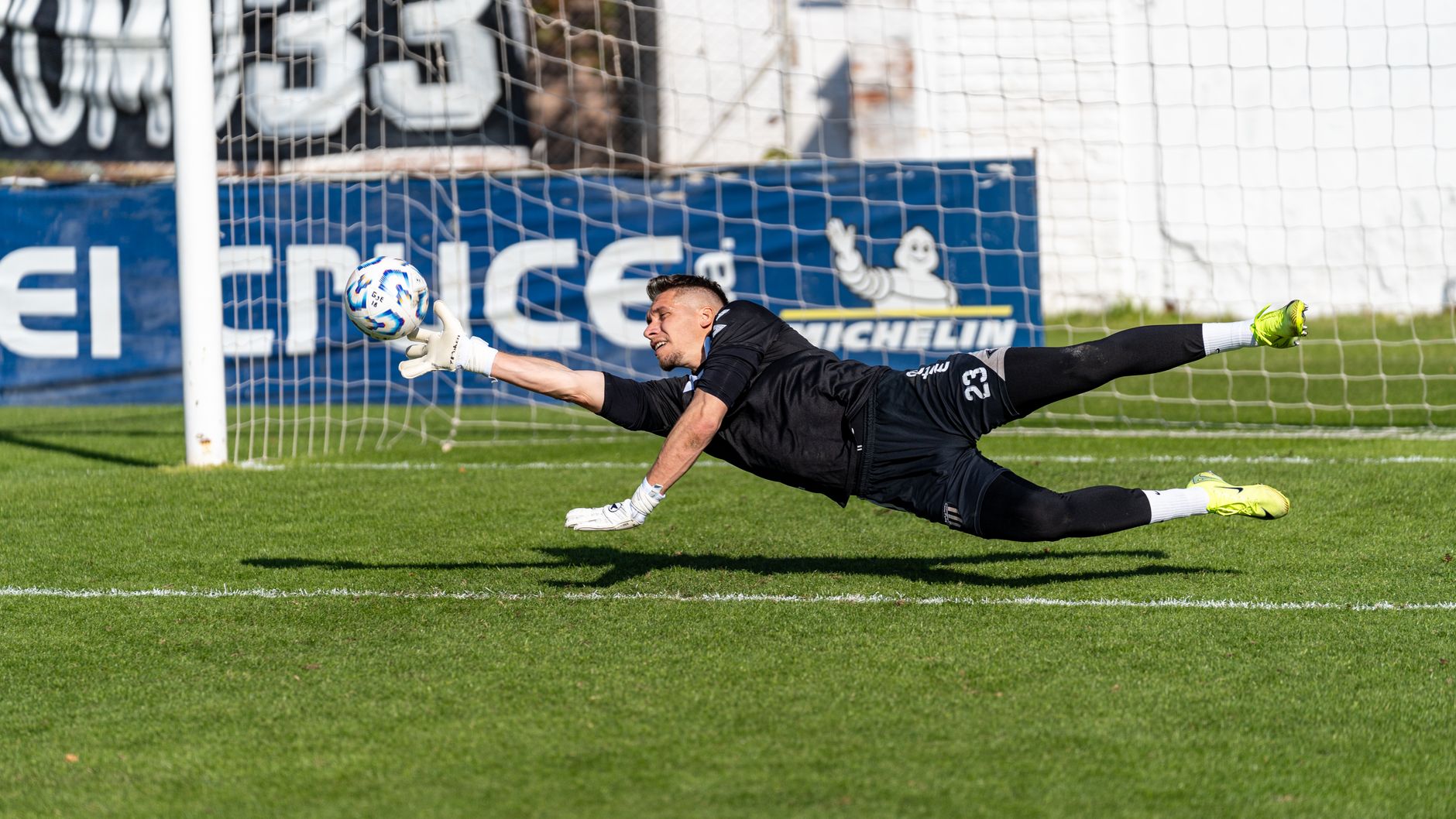 Goalkeeper in mid-air making a save during a football match.