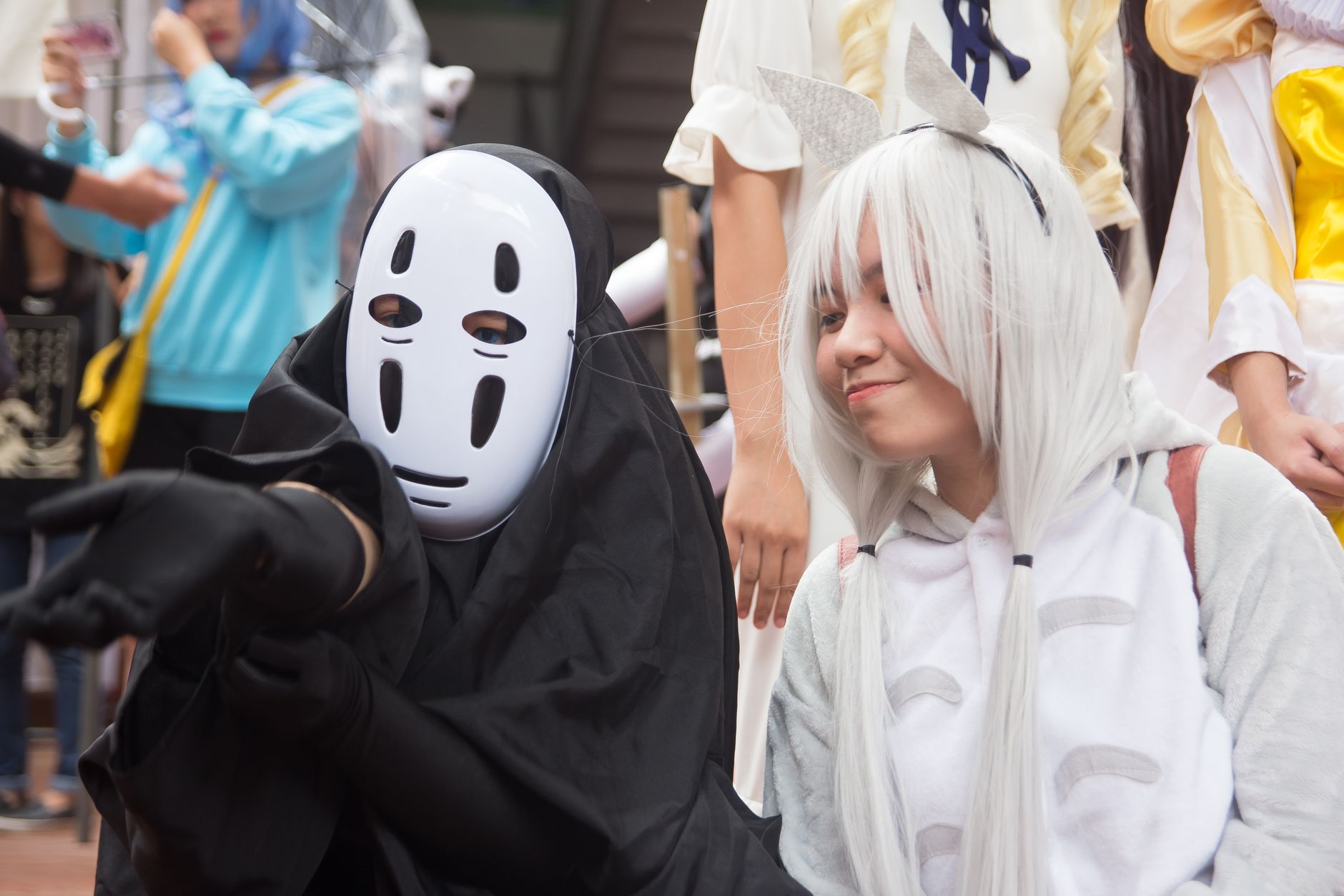Cosplayers in anime-themed costumes at a lively outdoor festival parade.