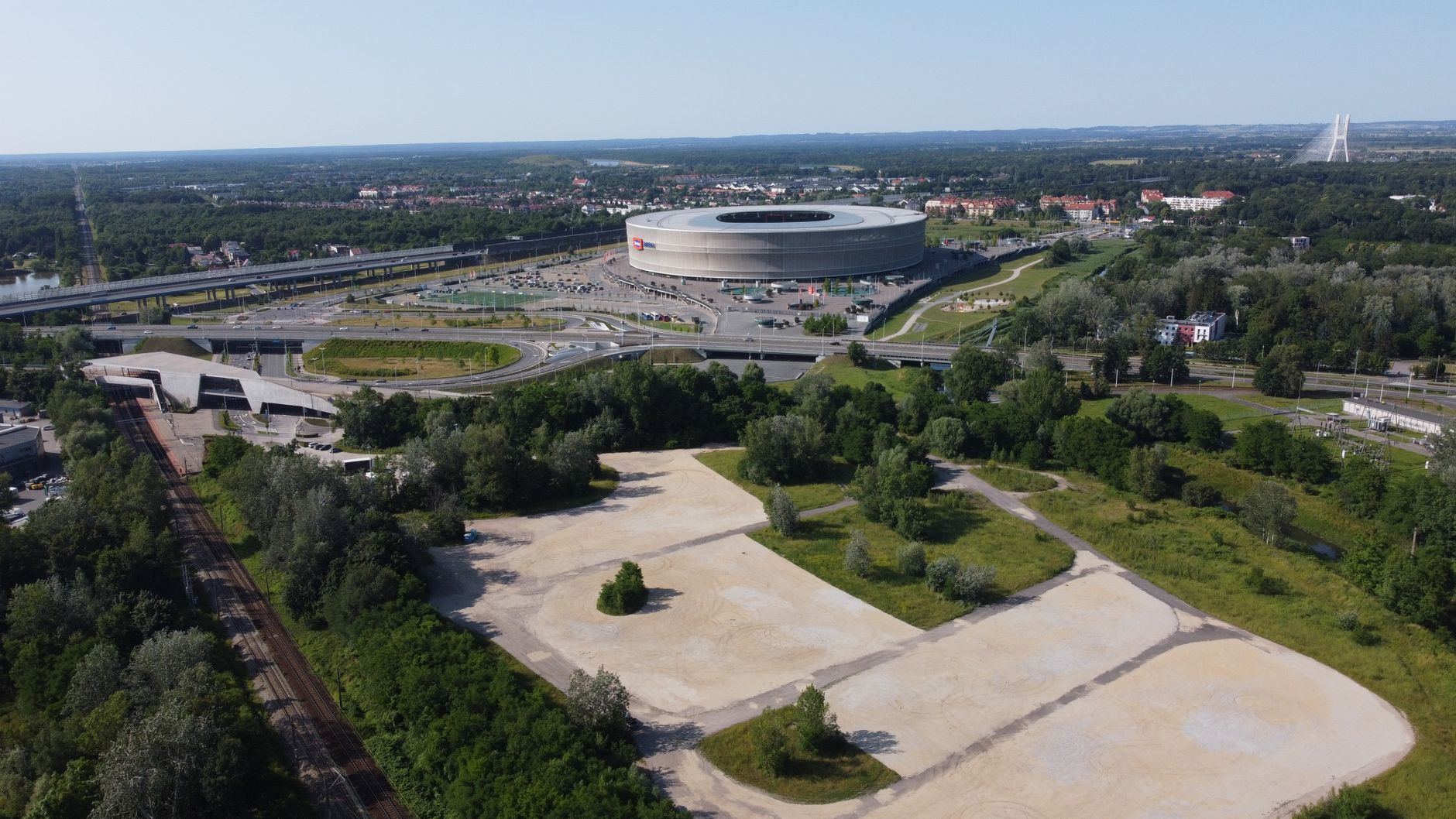 Aerial view of Wrocław Stadium in Poland on a sunny day, surrounded by greenery.