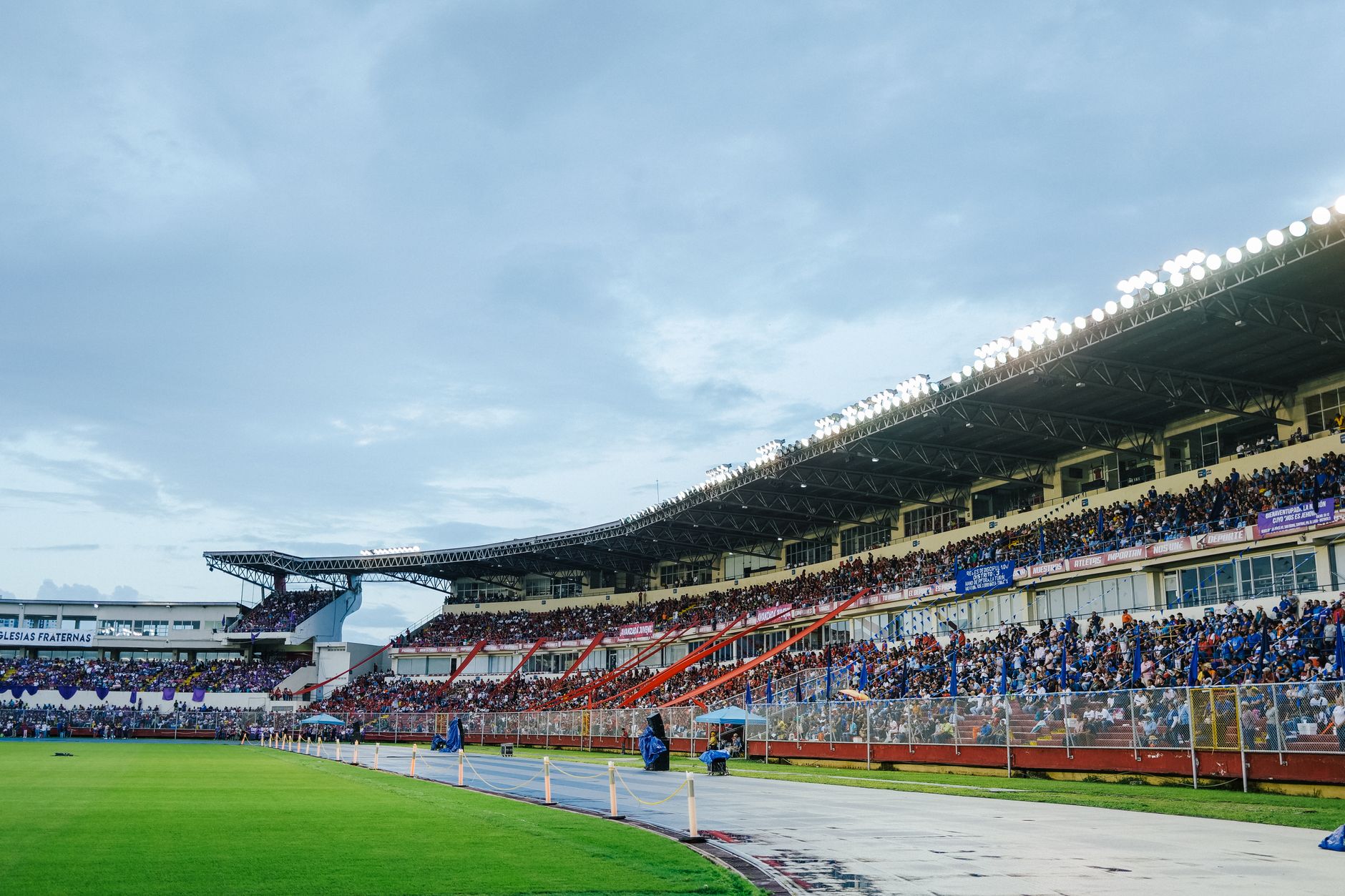 A packed stadium with enthusiastic spectators watching a live sports event under bright lights.