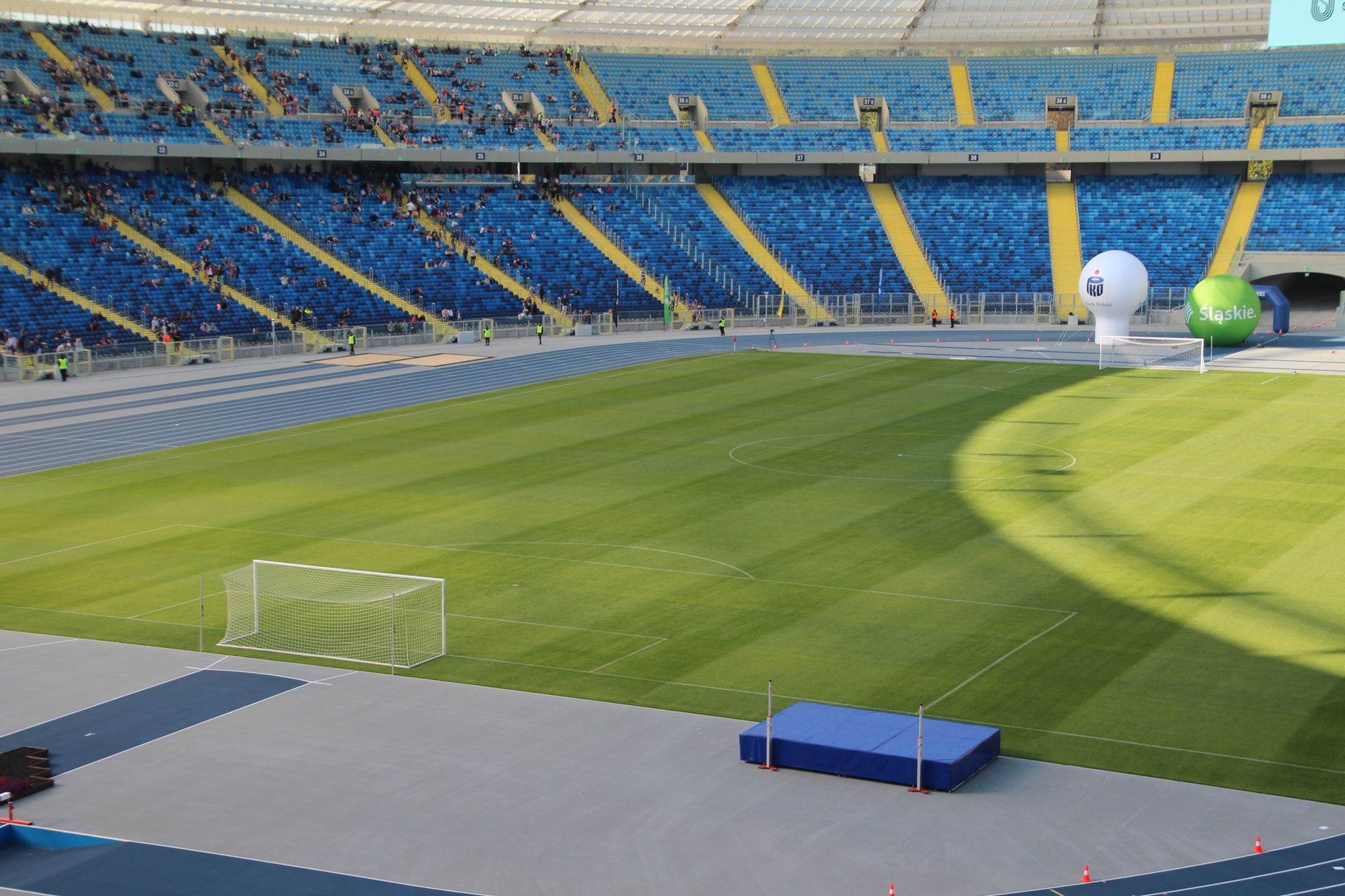 An expansive view capturing the vibrant blue seating and green field of a modern football stadium.